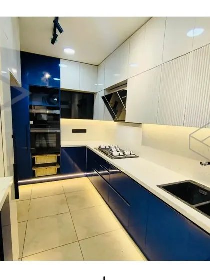 These images provide multiple angles of the stunning blue and white modular kitchen, showing details like the built-in oven tower, the fluted cabinet finish, and the overall clean and spacious layout.