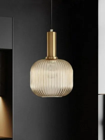 Here is the Cordelia pendant in a cylindrical shape, shown in a modern kitchen setting. Its warm, ribbed glass and simple form provide both functional light and a touch of sophisticated design.