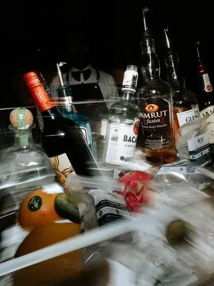 A chaotic and artistic shot of the bar at the end of the night. The motion blur and scattered bottles tell a story of a party well-celebrated.