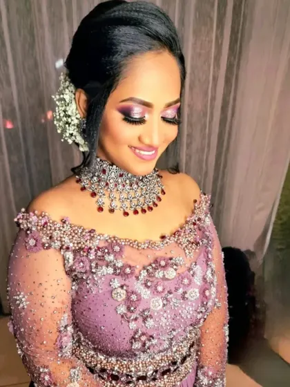 A glamorous reception look with an off-shoulder gown. The makeup features a shimmery purple smokey eye and a matching lip color.