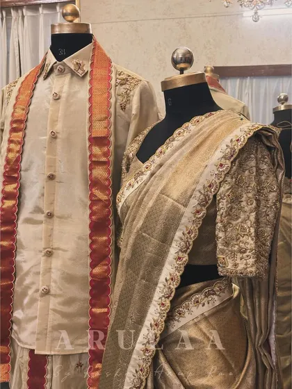 A beautifully coordinated 'Muhurtam' look for the bride and groom. His silk kurta features embroidery that complements the work on her blouse and saree border, creating a perfect picture of togetherness.