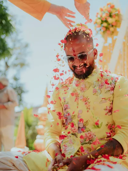 The groom is all smiles as he gets showered with petals. These golden moments are what make a Haldi ceremony so special.