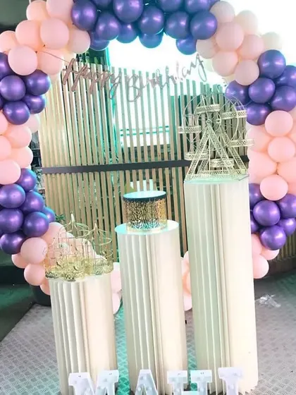A purple and pink balloon ring with modern white pedestals.
