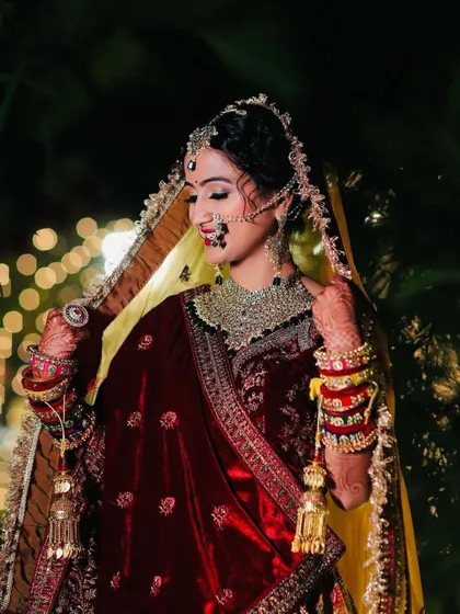 A beautiful pose showing the details of the bridal dupatta, jewellery, and the soft glam makeup with a classic red lip and nath.