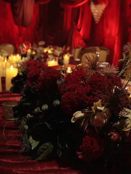 Another angle of the tablescape, showing the rich textures of the flowers and the velvet tablecloth. Every element is chosen to contribute to the overall theme of passionate elegance.