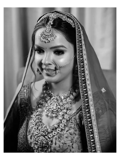 A classic black and white portrait of the bride, her gentle smile and intricate jewelry creating a timeless and elegant look.
