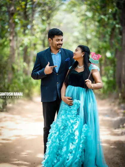 A candid interaction between the couple during their forest maternity shoot. The husband playfully points to the "It's a Girl" sign, a moment of pure, unscripted joy that we love to capture.