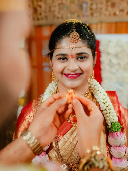 A close-up of the groom placing the sacred pendant on his bride, a pivotal and emotional moment in a Hindu wedding ceremony.