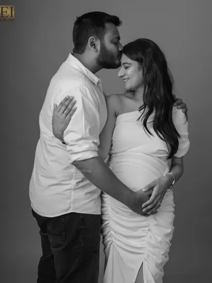 A tender forehead kiss in this black and white portrait symbolizes deep affection and partnership on the journey to becoming parents.