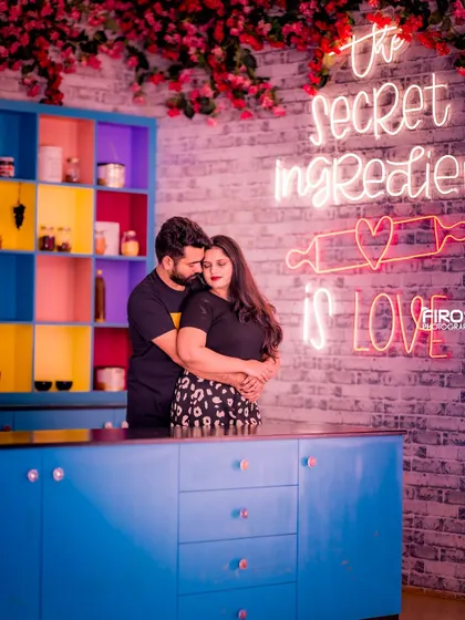 A fun and unique shot in a colorful, retro-style kitchen set. The neon sign "The secret ingredient is LOVE" adds a playful and modern touch to this intimate portrait.