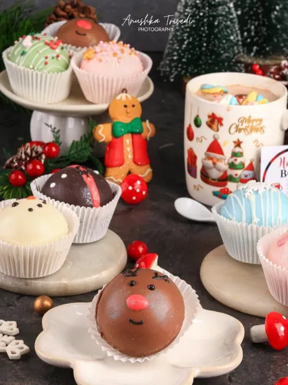 A playful assortment of hot cocoa bombs decorated as reindeer and snowmen, perfect for a fun Christmas treat.