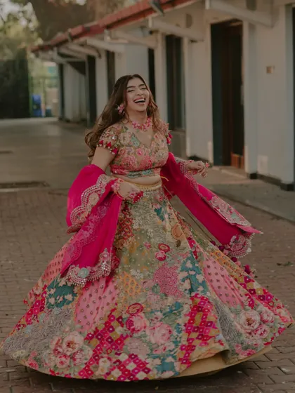 A full-length shot of the bride twirling with a joyous laugh, her colorful lehenga creating a beautiful motion.