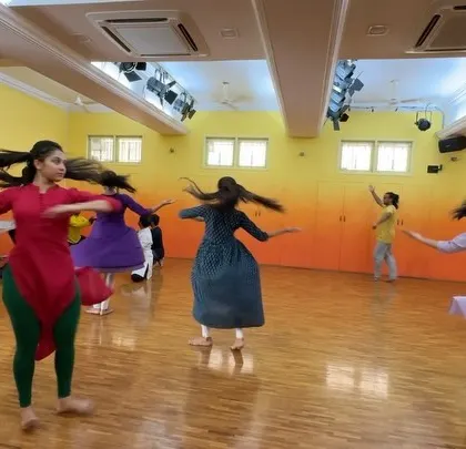The dancers moving with energy and joy during a studio rehearsal. Even in practice clothes, the spirit of the dance shines through.