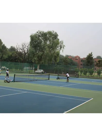 An overview of the tennis facility at Modern School, with several courts in use. The green surroundings and well-kept grounds provide a pleasant atmosphere for competitive play.
