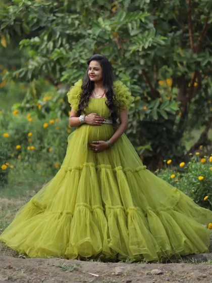 A full-length shot of the lime green ball gown in a field of yellow flowers. This image shows the beautiful volume and texture of the dress in a natural environment.