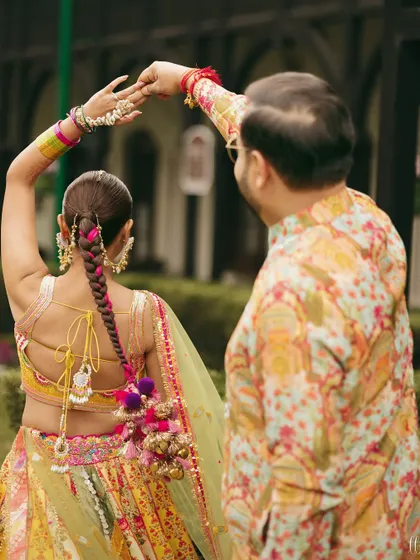 A closer look at the back of the bride's outfit, showing off her beautiful braided hairstyle with colorful tassels that match her vibrant lehenga.