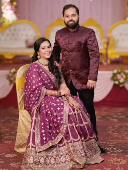 Another elegant portrait of the engaged couple. The bride is seated while her partner stands beside her, creating a timeless and well-composed photograph.