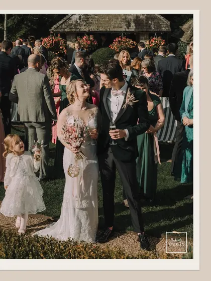A full-length view of the couple amidst their guests, capturing the vibrant and social atmosphere of their garden wedding.