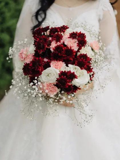 A close up of the Christian bride's beautiful bouquet, a mix of deep red, pink, and white flowers. This detail shot adds a touch of classic romance to the wedding gallery.