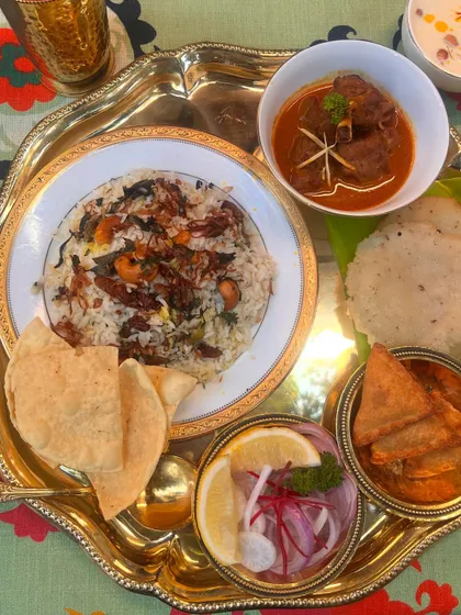 A close-up of our Eid special thali. It features fragrant Thalassery Biryani, a rich mutton curry, crispy pappadams, and fresh onion salad, offering a complete and satisfying festive meal.