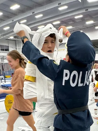 A young police officer puts the finishing touches on their mummy creation. Our interactive games are designed to encourage teamwork and creativity in a fun, high-energy setting.