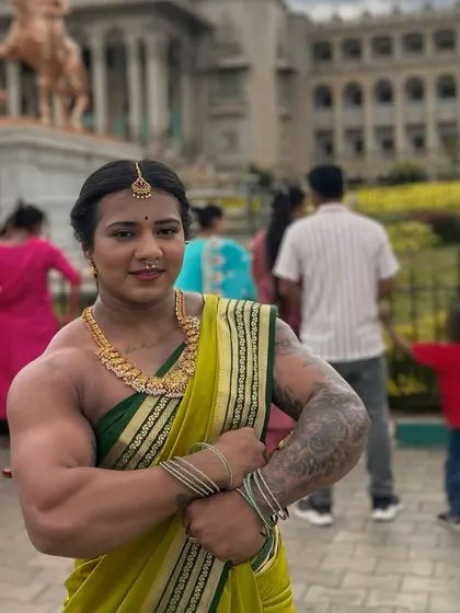 A full-body shot in a green saree, showing a confident, arms-crossed pose that emphasizes my physique against the backdrop of a significant landmark.