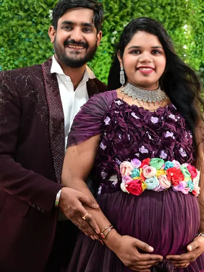 A close-up of a happy couple during their maternity shoot. She is wearing our purple ruffle gown with a colorful floral belt accessory.