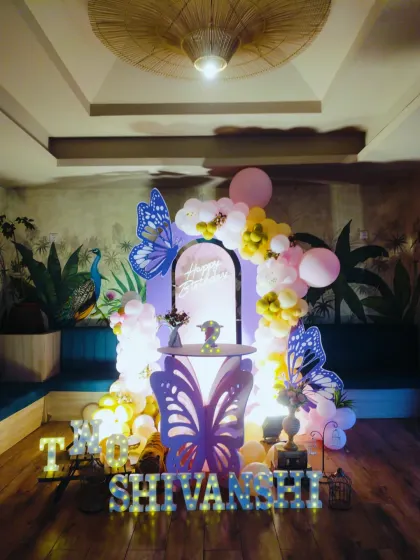 A sweet and simple butterfly theme for Shivanshi's second birthday. This setup includes a butterfly-shaped table, large blue butterfly cutouts, and a light-up name sign, perfect for an intimate celebration.
