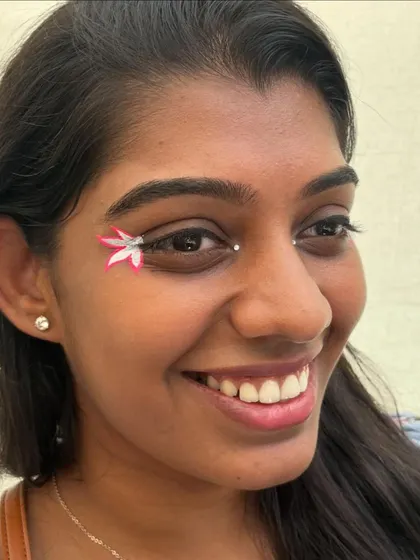 A delicate and artistic look with a hand-painted flower on the outer corner of the eye. This shows how makeup can be used for detailed, artistic expression.