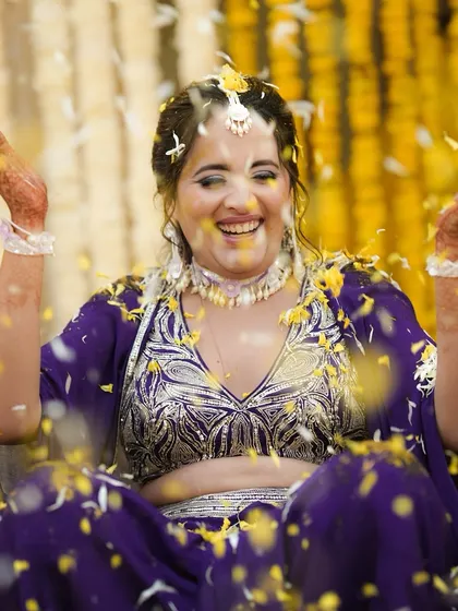 A moment of pure joy as the bride is showered with flowers during her Haldi, her smile lighting up the frame.