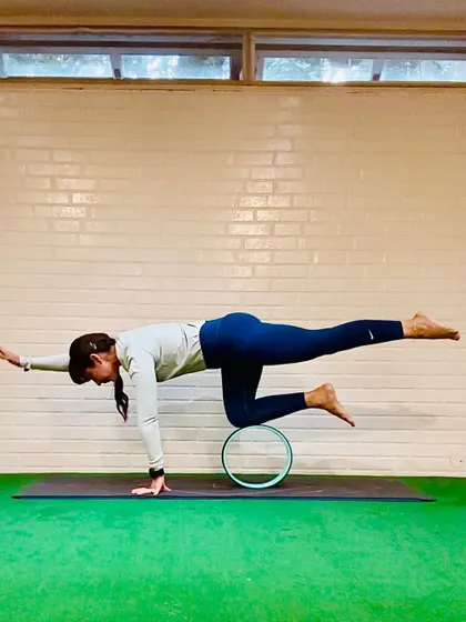 The yoga wheel can be a wonderful tool for exploring balance and stability. Here, I am practicing a bird-dog variation with my knee on the wheel. This challenges the core and improves proprioception, helping you find strength even in unstable positions.