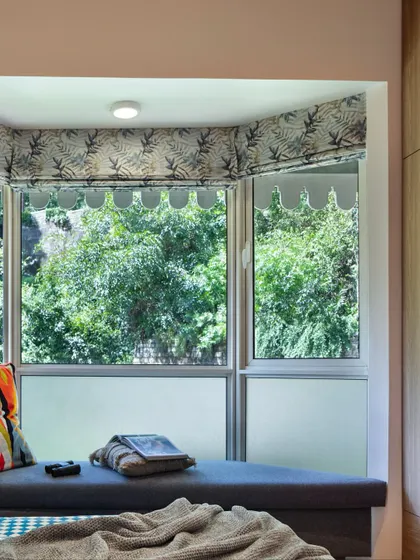 The bay window nook in the kids' bedroom, framed by foliage-printed drapes. This cozy corner is designed for reading, napping, or simply watching the clouds roll by over the mountains.