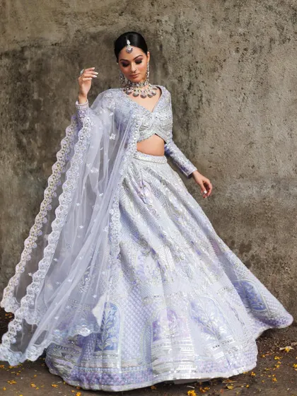 We adore pastel shades for modern wedding functions. This full-length view shows a gorgeous lavender lehenga with intricate silver mirror work and a beautifully detailed border on the dupatta, offering a soft yet glamorous look for an engagement or sangeet.