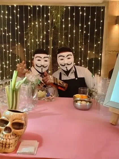 Another example of a themed bar, with masked bartenders, a custom menu, and unique skull-shaped tiki mugs for serving cocktails.