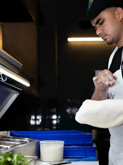 A pizzaiolo shaping the dough. This crucial step creates the foundation for our signature airy crust.