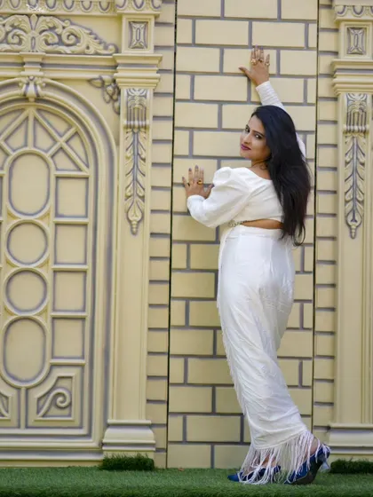 A confident pose against a modern architectural element, showcasing a stylish look.