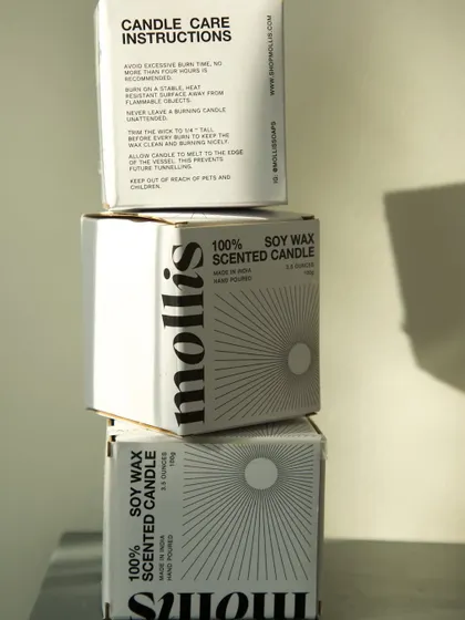 A stack of my 100% soy wax candle boxes, showing the minimal design and integrated care instructions.