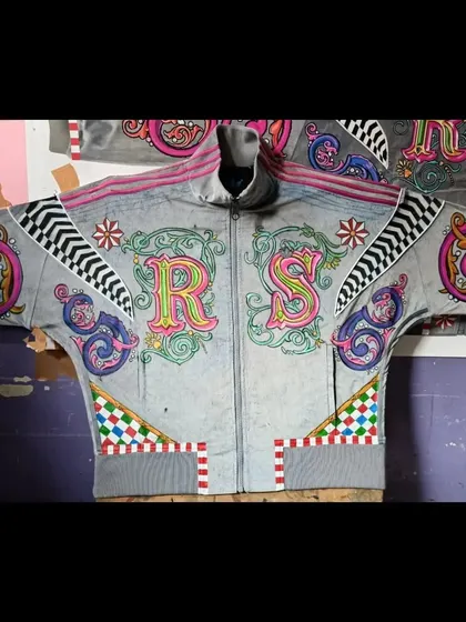 A full, flat-lay view of the completed 'RS' initialed hoodie. This perspective showcases the entire composition, from the central letters to the decorative elements on the shoulders and waistband.