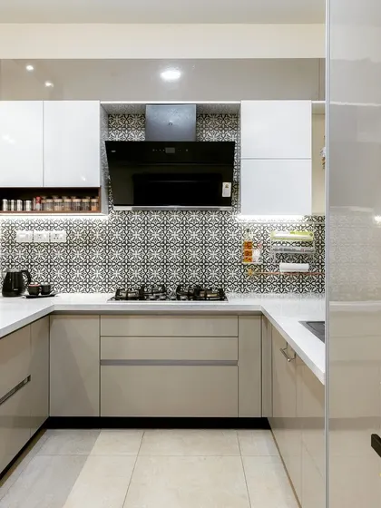 A U-shaped kitchen with glossy beige cabinets and a patterned tile backsplash. The design includes a dedicated space for a microwave and other appliances.