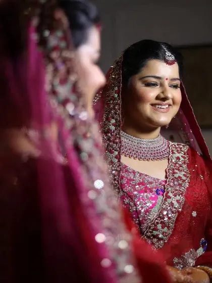 A candid shot of the bride looking at her reflection in the mirror, smiling as she gets ready.