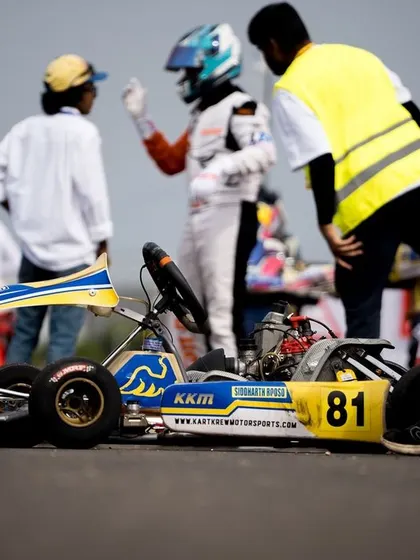 A kart sits on the grid, with a mechanic and driver discussing strategy.
