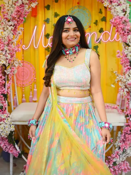 The beautiful bride-to-be at her Mehendi ceremony. Her colorful lehenga and floral jewelry are perfect for the festive occasion.