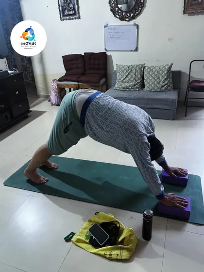 A client in Adho Mukha Svanasana (Downward-Facing Dog) with hands on blocks. This elevates the hands, making the pose more accessible and reducing pressure on the wrists and shoulders.