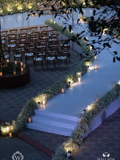 The outdoor lounge area for a reception, illuminated by fairy lights and candles. The elegant white furniture and surrounding greenery created a cozy and romantic space for guests to relax.