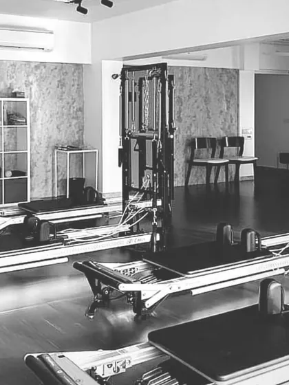 A black and white shot of our studio space, highlighting the clean lines of the reformers and the calm, focused atmosphere we cultivate.