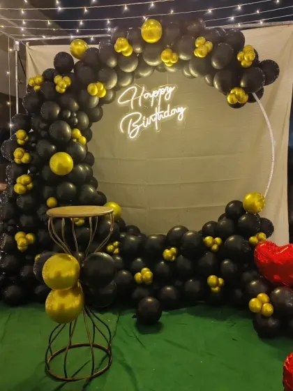 Another view of the black and gold birthday balloon arch, showing how it looks with the surrounding fairy lights. This setup is great for creating a focused party corner on a terrace or in a garden.
