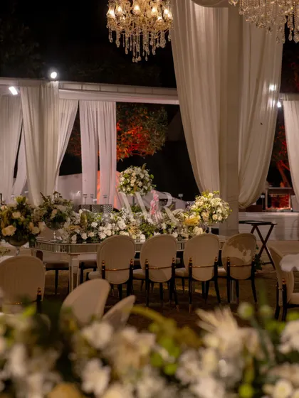 A view of the elegant dining setup, with a mirrored table reflecting the dozens of chandeliers and white floral arrangements. This design was all about creating "whispered grandeur" for a 2-day destination wedding.