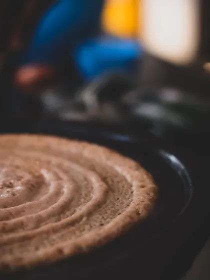 A close-up of a dosa on a traditional cast-iron tawa. The concentric rings show a practiced hand, a skill we teach in our Indian cuisine classes.