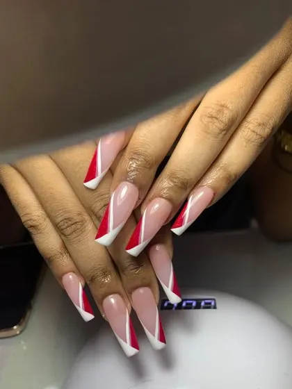 A long, coffin-shaped French manicure with a dramatic, angular design. The red and white tips create a sharp, geometric look that is both modern and bold.
