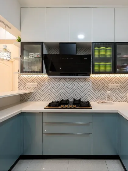 A modern U-shaped kitchen in a calming pastel blue and white. The geometric backsplash adds a contemporary touch, while the open pass-through counter connects it to the dining area.